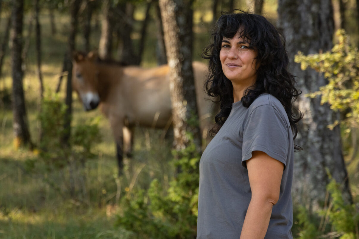 Soraya Espinosa, owner of nature tourism business, El Observario, in front of a przewalski's horse. Iberian Highlands, Spain.